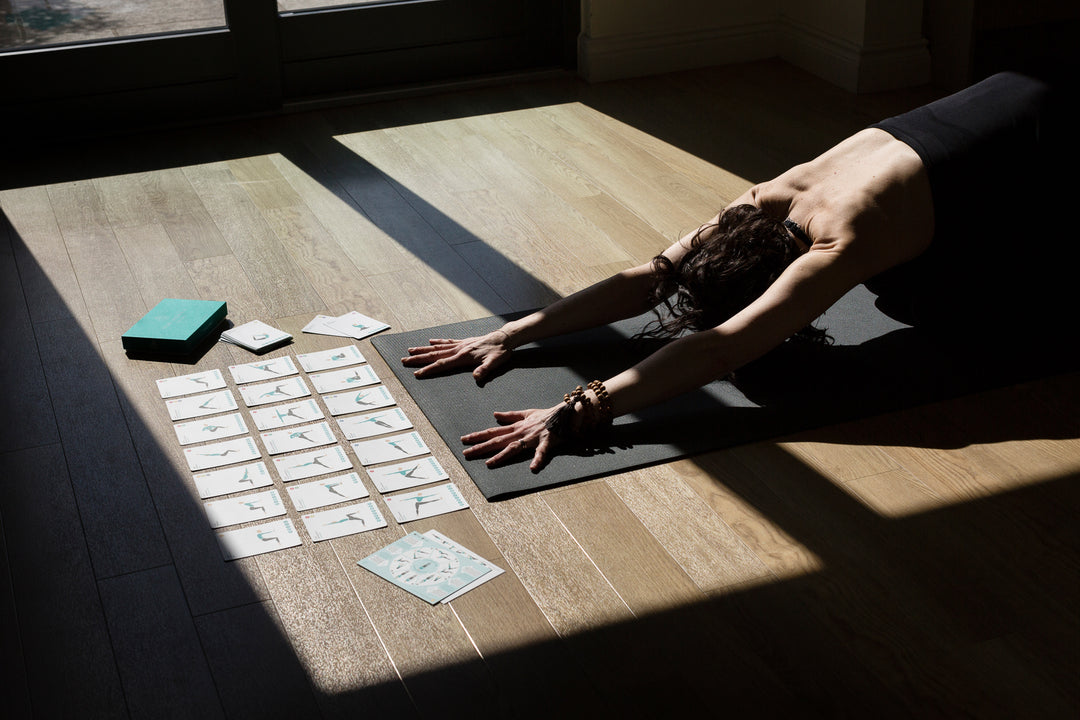 Ruth Delahunty kneeling arms outstretched on her yoga mat with an asana sequence using her 108 Asana Cards laid out in front of her | Yogaru | Eco Yoga Store