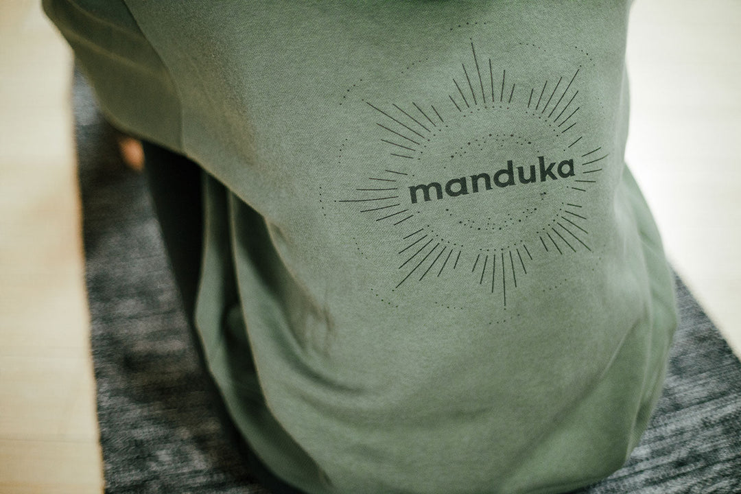 Close-up of Manduka decal on back of T-shirt being worn | Manduka | Eco Yoga Store