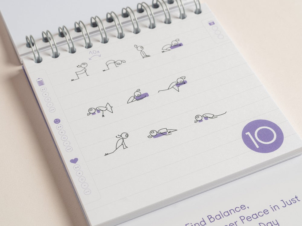 A close-up of an open spiral-bound '30-Day yoga Challenge' with lined pages, featuring simple line drawings of yoga poses in black and purple, a purple circle with the day sequence, number 10, and partial text at the bottom - Yoga Journaling | Eco Yoga Store