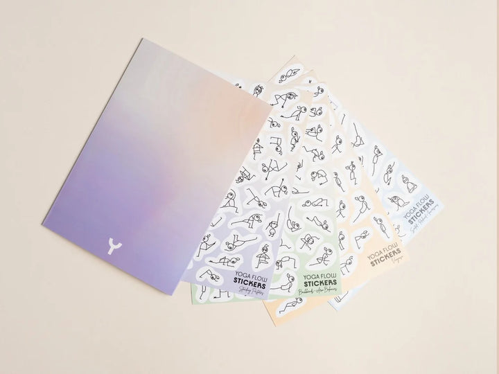 A set of Stick Play Flow Yoga Pose sticker sheets fanned out on a light beige background. The sheets 
feature minimalist black line drawings of people in yoga poses - Yoga Journaling | Eco Yoga Store