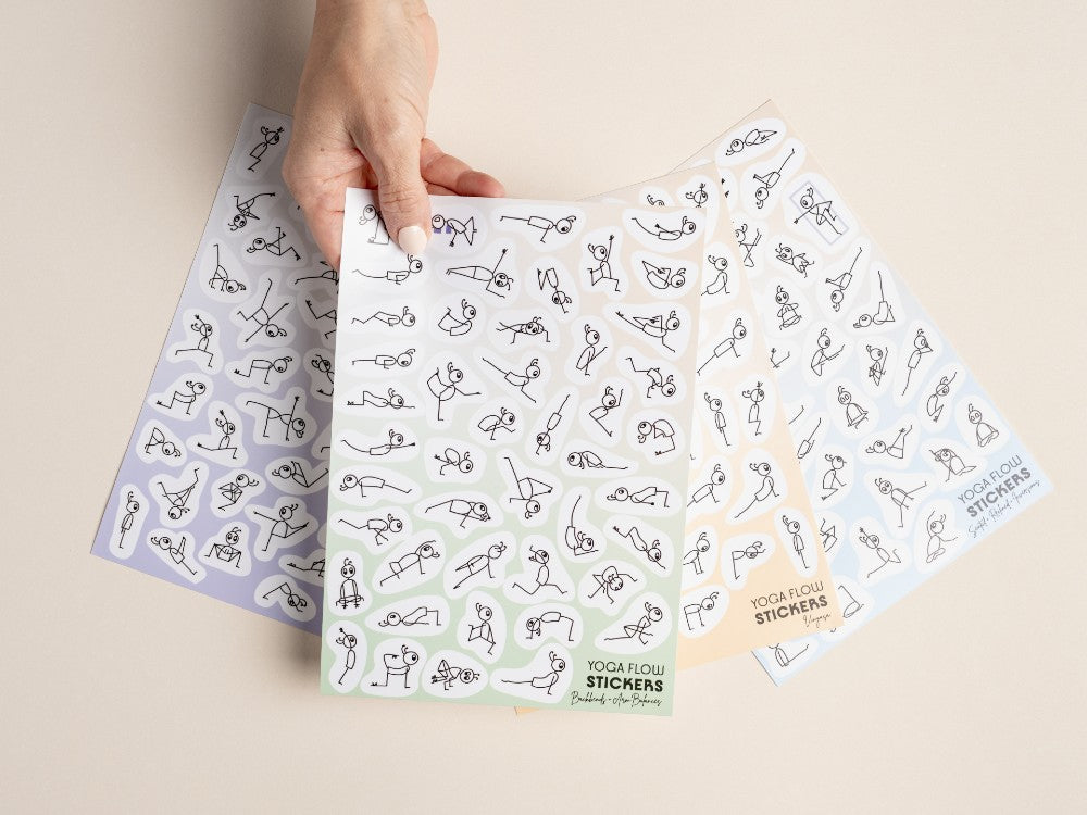 A hand holds a sheet of yoga flow stickers with black line drawings of poses on a light beige background - Yoga Journaling | Eco Yoga Store