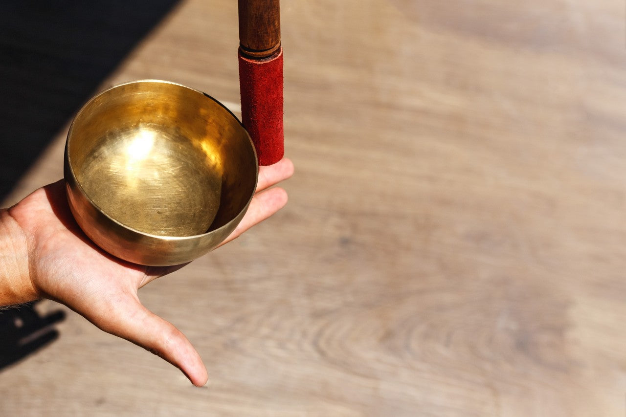 Tibetan Singing Bowl - bowl sitting on palm of hand with tip of striker resting on fingertips - TRIBE | Eco Yoga Store