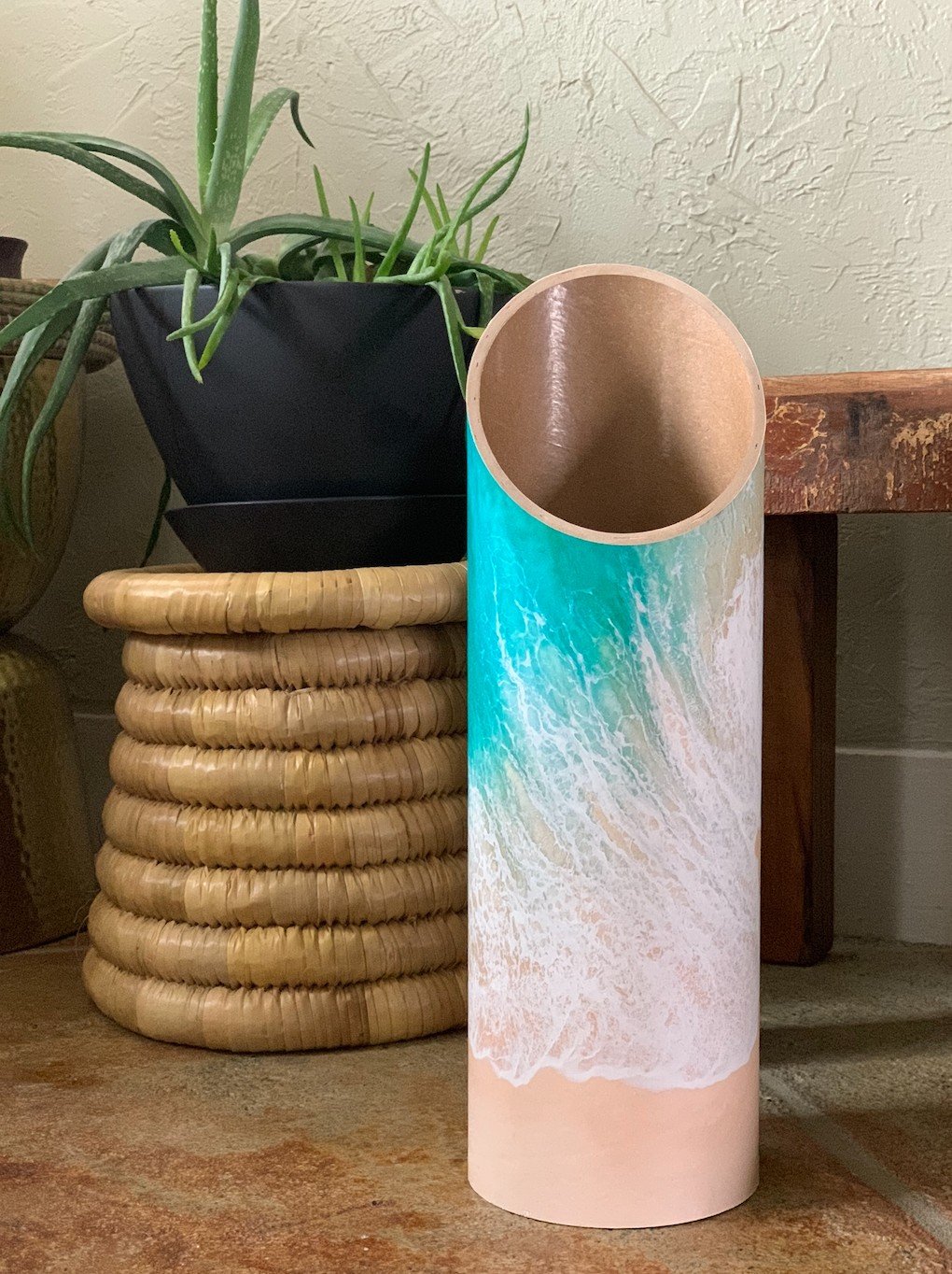 Homi Yoga Mat Tube - Beachy design -  standing on wooden floor next to a plant pot - Mache | Eco Yoga Store