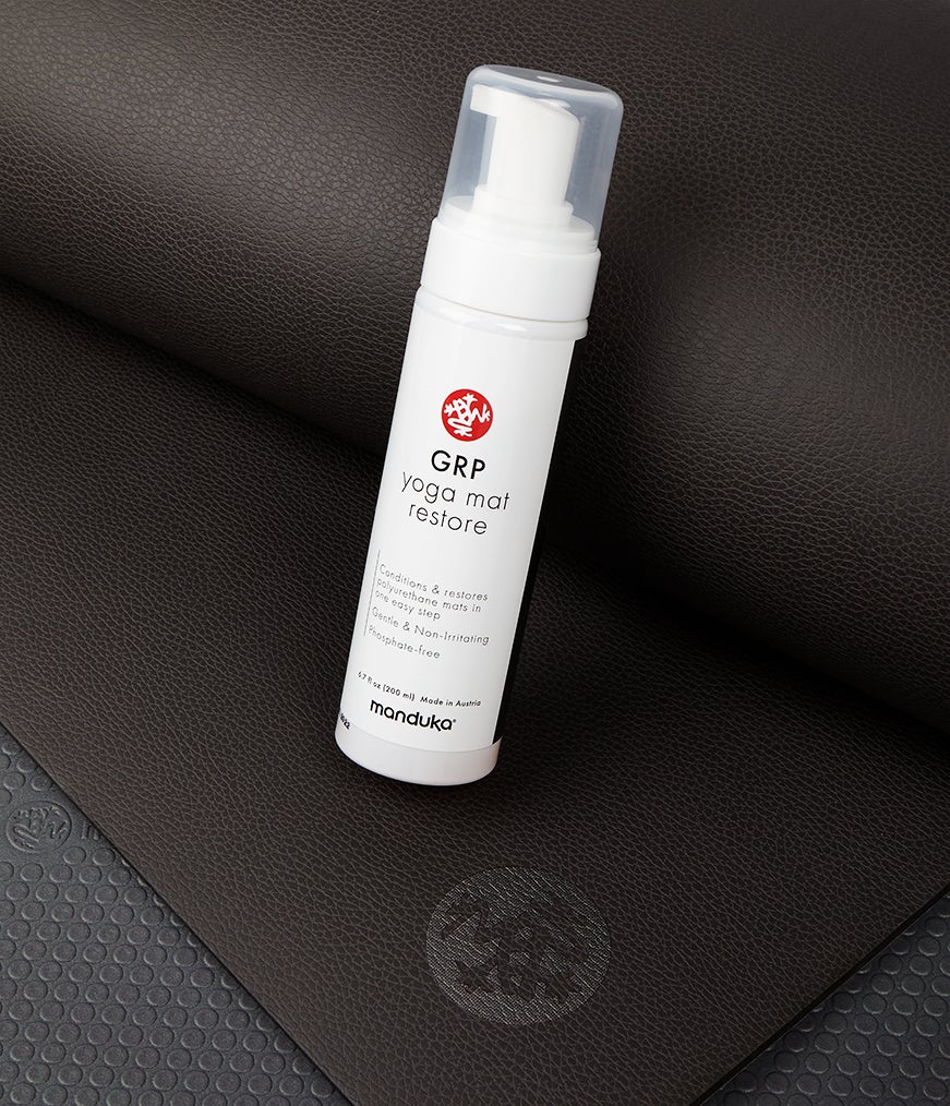 Manduka GRP Yoga Mat Restore - 200ml bottle sitting on a GRP Yoga Mat | Eco Yoga Store